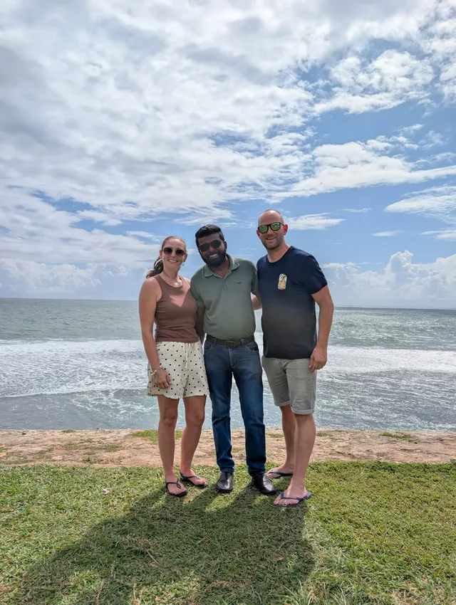 Two guests with Dhanuka on the coast, the sea behind them