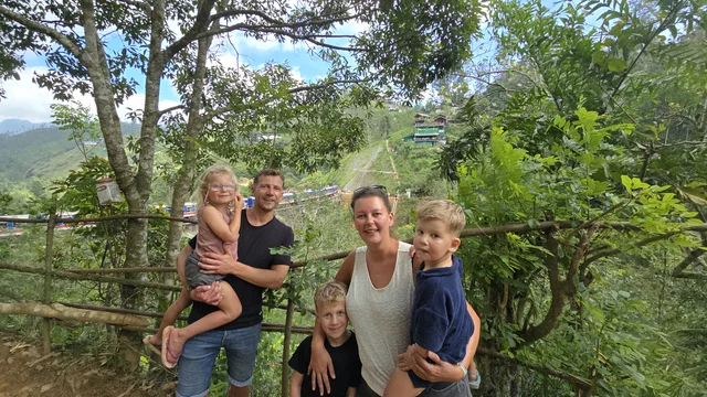 A family of five together at a green hillside viewpoint