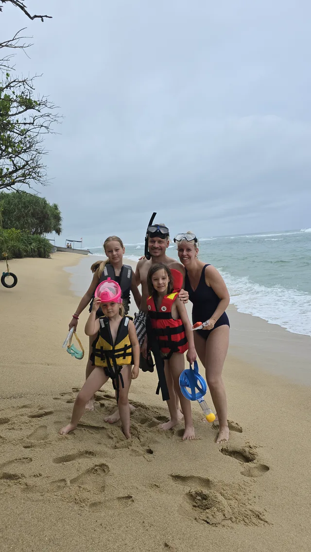 A family of five on a beach in snorkel gear and life jackets